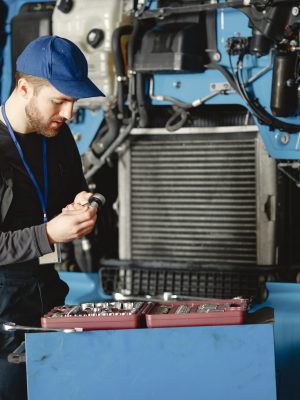 Men repair a truck. Man teaches repair a car. Two men in uniform